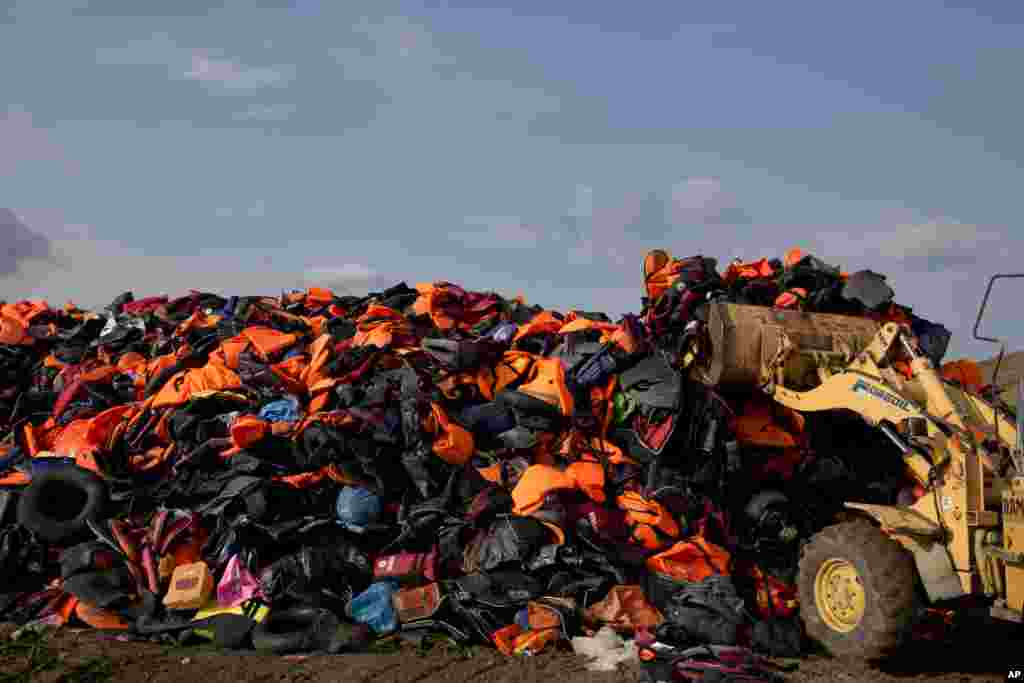An excavator works on a huge pile of life vests and dinghies that have been used by migrants at a local dump of the island of Lesbos, Sept. 24, 2015.