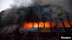Locals and fire-fighters try to control a fire at a garment factory in Dhaka, March 6, 2014. 