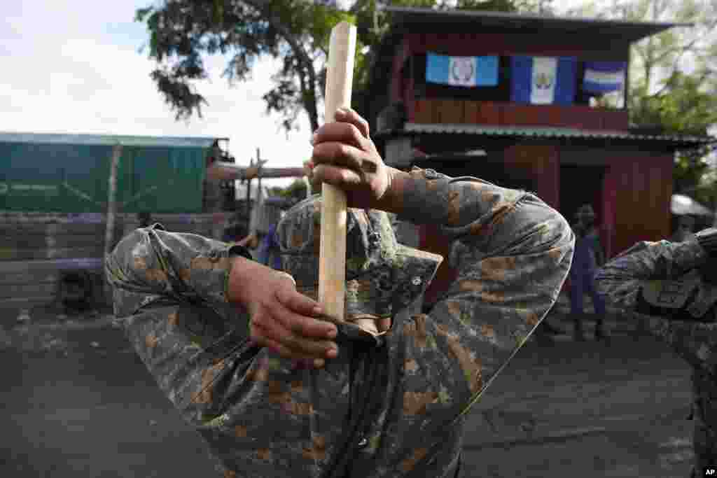 A soldier places a handmade, wooden stick into the back of his uniform as he stands guard in El Cinchado, Guatemala, on the border with Honduras. Guatemala vowed to detain and return members of a caravan of about 2,000 migrants hoping to reach the U.S. 