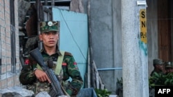 (FILES) This photo taken on November 9, 2023 shows a fighter of the ethnic armed group Ta'ang National Liberation Army (TNLA) standing guard in the town of Namhkam in northern Shan state.