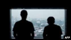 Dua pria asal Indonesia yang pernah menjadi korban perdagangan manusia dan dipaksa bekerja untuk penipuan daring di Kamboja, berfoto di Jakarta, 15 Oktober. (Foto: Yasuyoshi Chiba/AFP)