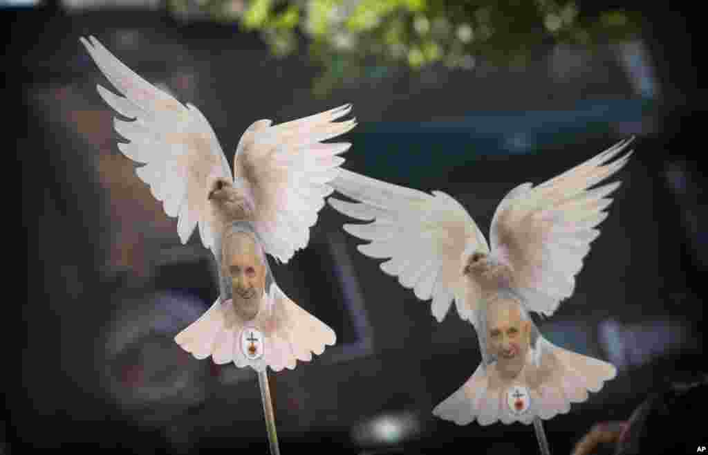 People hold pictures of Pope Francis framed in the the shape of a dove, as they wait for him in Mexico City, Mexico.