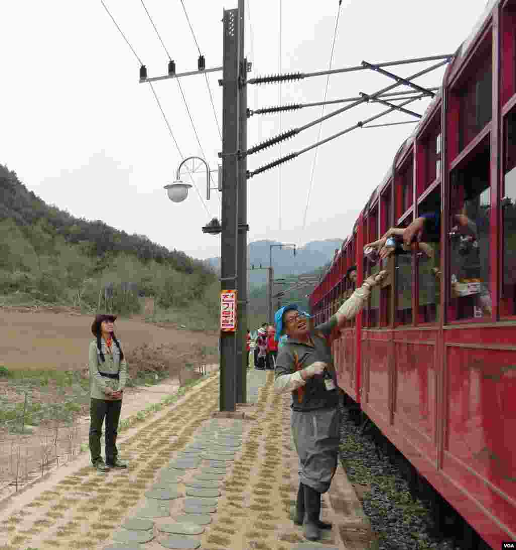 A farmer steps out of his field to exchange eggs for beer from V-train passengers during a brief stop at a rural station, May 9, 2013. (R. Kalden/VOA)