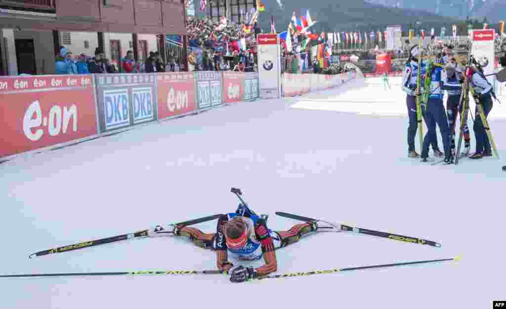 Athletes of the Italian team (R) celebrate their victory as Franziska Preuss of the second placed German team lays down in the finish area during the women&#39;s 4x6 km relay event during the IBU Biathlon World Cup in Hochfilzen, Austria.