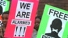 FILE - Protestors for press freedom hold placards outside the Harare Magistrate's Court.