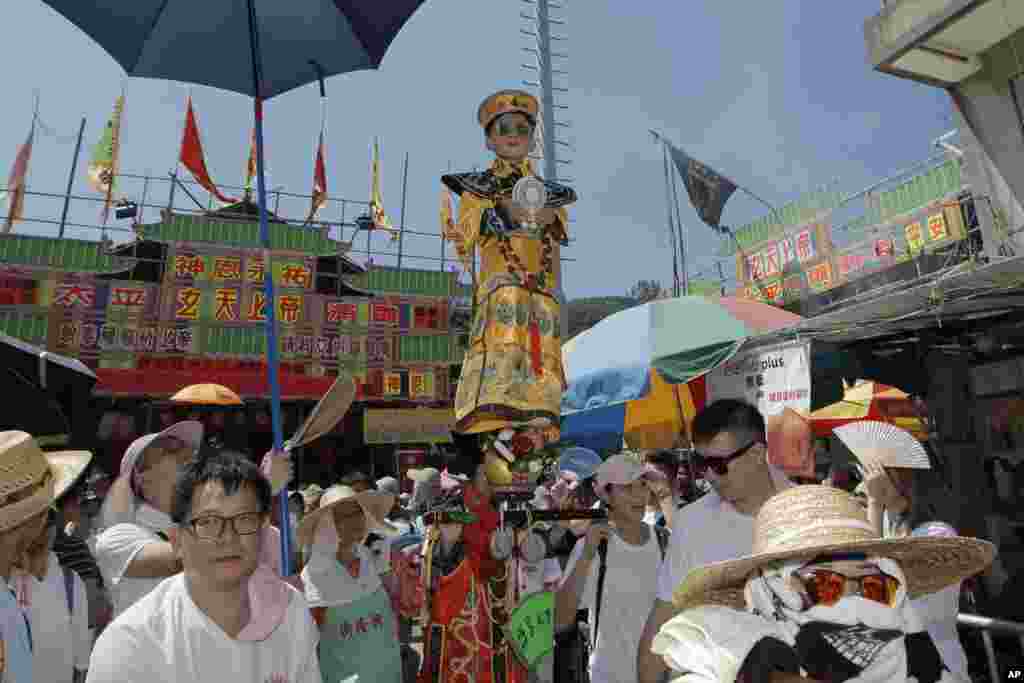 ក្មេង​ម្នាក់ស្លៀកពាក់​ប្រពៃណី​ចិន​ត្រូវ​អណ្តែត​លើអាកាស​អំឡុង​ការហែក្បួន​នៅ​កោះ Cheung Chau ទីក្រុង​ហុងកុង​ដើម្បី​អបអរ​ពិធីបុណ្យ Bun។