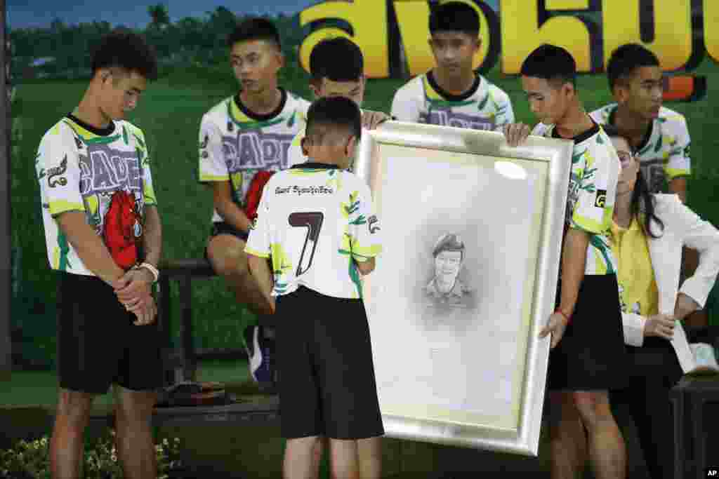 គ្រូបង្វឹក Ekkapol Janthawong (ឆ្វេង)​ និង​កុមារ​១២​នាក់​ក្នុង​ក្រុម​បាល់ទាត់​ដែល​បាន​ជាប់​ក្នុង​ល្អាង​ភ្នំ​ផ្តល់​ការ​គោរព​ដល់​លោក​ Saman Gunan អ្ន​ក​មុជ​ទឹក Thai SEAL ចូល​និវត្តន៍​ម្នាក់​ដែលបាន​ស្លាប់​អំឡុង​ការ​សង្រ្គោះ​ដំបូង​របស់​ពួកគេ​ នៅ​ក្នុង​សន្និសីទ​កាសែត​ក្នុង​ទីក្រុង​ឈៀង​រ៉ៃ​ប្រទេស​ថៃ។