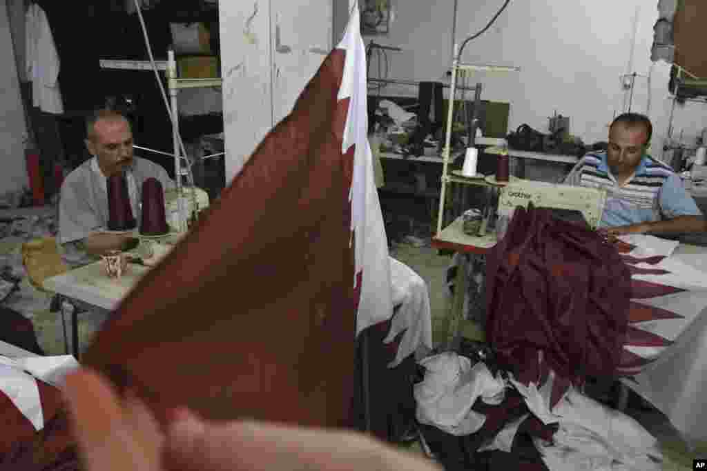 Palestinian tailors Eyad Absi, left and Salama Ashour make Qatari flags in a shop for Tuesday's official visit of the Emir of Qatar Sheikh Hamad bin Khalifa al-Thani in Gaza City, October 21, 2012.