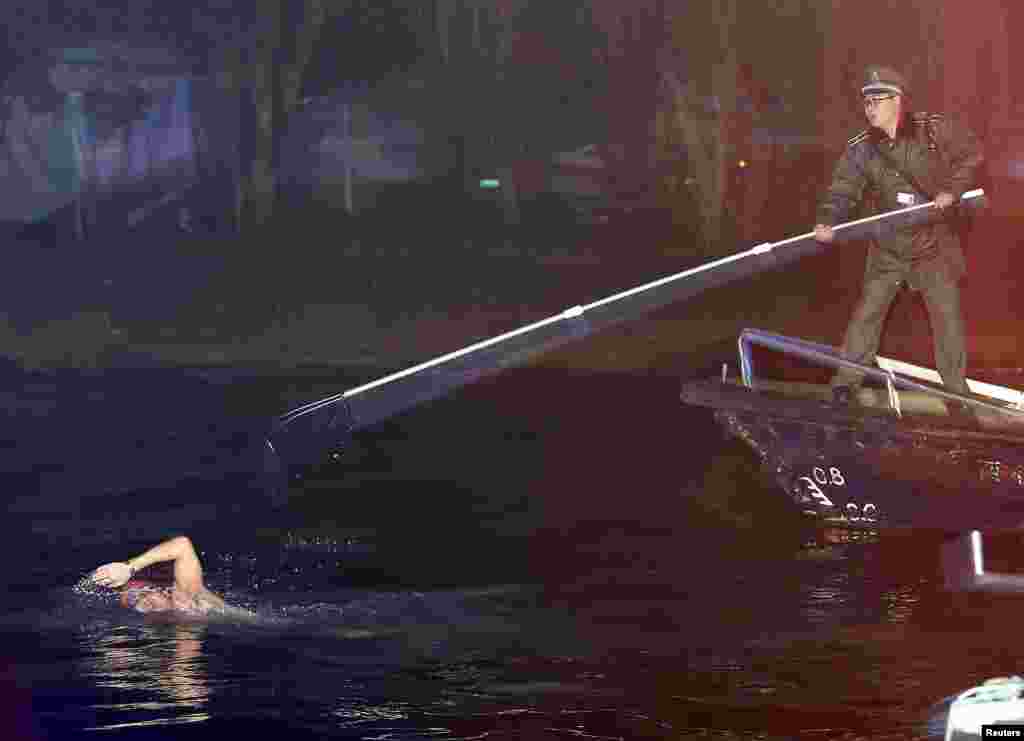 A security guard tries to stop a man from swimming away after being caught swimming in the West Lake, which is a violation of the resort&#39;s regulations, in Hangzhou, Zhejiang province, China.