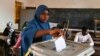 Une femme dépose son bulletin de vote dans l'urne à Niamey, le 27 décembre 2020, lors des élections présidentielles et législatives du Niger.