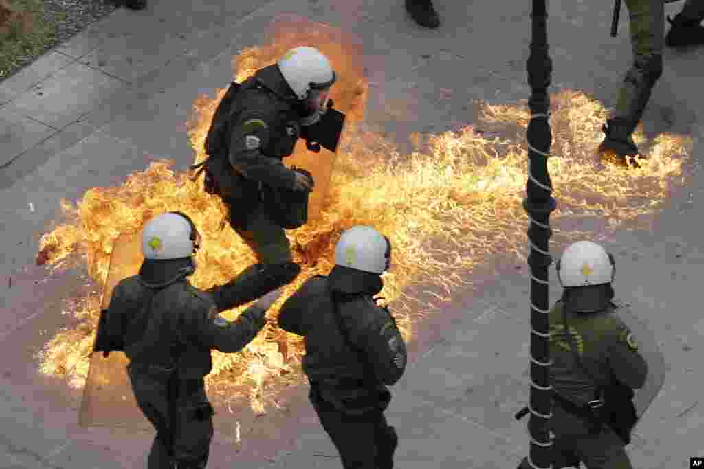 Riot policemen try to avoid a petrol bomb thrown by protesters during a 24-hour nationwide general strike in Athens, Greece. Clashes broke out between police and youths throwing fire bombs and stones, as tens of thousands of people marched through central Athens to protest planned pension reforms.