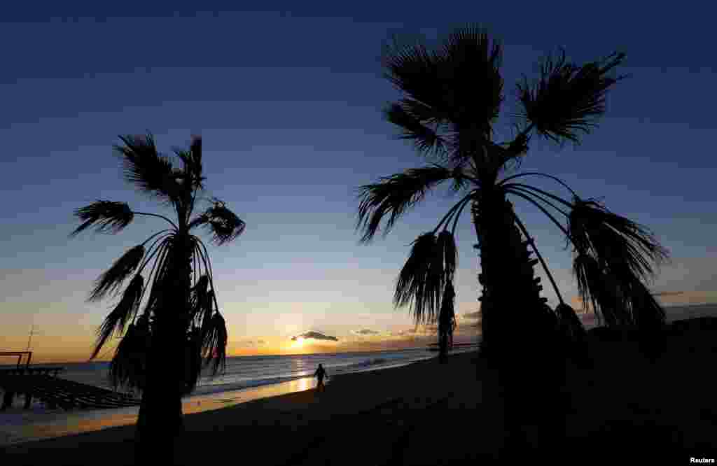 A woman walks on the beach at sunset in the Mediterranean resort town of Belek in Antalya, Turkey.