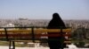 A woman sits on a bench overlooking Aleppo's ancient citadel and the old city, Syria April 13, 2019. 