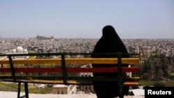 A woman sits on a bench overlooking Aleppo's ancient citadel and the old city, Syria April 13, 2019. 