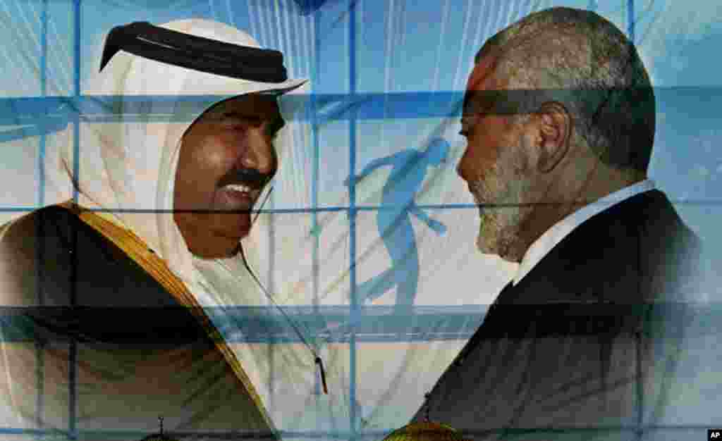 A Palestinian worker walks behind posters of the Emir of Qatar Sheikh Hamad bin Khalifa al-Thani, left, and Gaza's Hamas Prime Minister Ismail Haniyeh, right, in preparation for the upcoming visit to Gaza at Palestine Monday, Oct. 22, 2012.