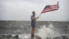 Jutjuber Mark Pejton drži američku zastavu dok pozira svom bratu Metu Pejtonu na obali uoči dolaska uragana Helene u Aligator Point, Florida, 26. septembra 2024.