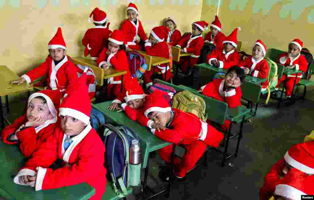 កុមារជាច្រើនស្លៀកពាក់ឈុត Santa Claus អង្គុយក្នុងថ្នាក់រៀនមួយមុនពេលចូលរួមពិធីបុណ្យគ្រឹស្តស្មាសនៅក្នុងសាលានៅទីក្រុង Chandigarh ប្រទេសឥណ្ឌា។