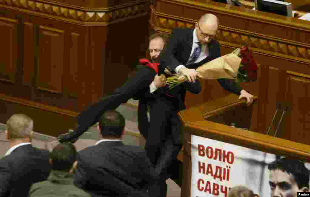 Rada deputy Oleg Barna removes Ukrainian Prime Minister Arseny Yatseniuk from the podium, after presenting him a bouquet of roses, during a session of parliament in Kyiv. Other Rada deputies scuffled with their colleague Barna immediately after the incident.