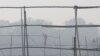 FILE - A laborer dismantles scaffolding near the India Gate war memorial on a smoggy day in New Delhi.