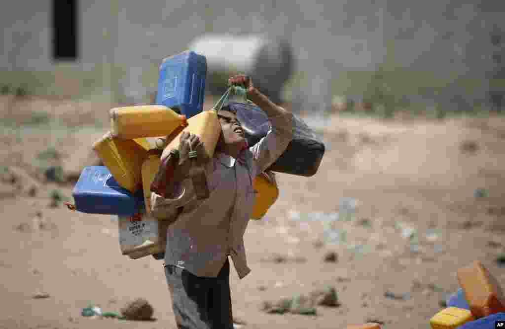 A boy carries buckets to fill with water from a public tap amid an acute shortage of water, on the outskirts of Sana'a, Yemen.