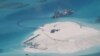 FILE - In this Feb. 25, 2014 file photo taken by surveillance planes and released May 15 by the Philippine Department of Foreign Affairs, a Chinese vessel, top center, is used to expand structures and land on the Johnson Reef, called Mabini by the Philippines and Chigua by China, at the Spratly Islands in the South China Sea, Philippines. 