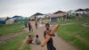 FILE - A Rohingya boy walks with a mat as children play in the background at Dar Paing camp for Muslim refugees in north of Sittwe, western Rakhine State, Myanmar. 