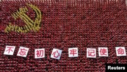 中国浙江省金华市的中共党员手举“不忘初心牢记使命”的标语牌组成中共党旗图案的阵仗。（2019年6月28日）