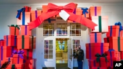 A Marine White House Military social aide holds the door to the East Wing entrance of the White House during a press preview of the White House holiday decorations, Nov. 29, 2021.