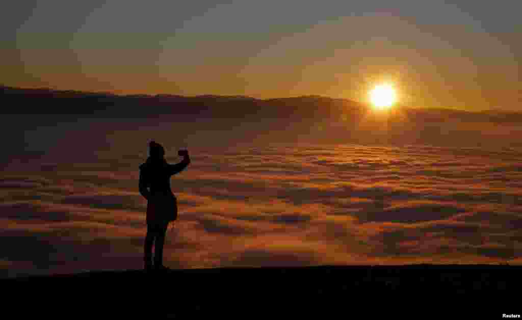 A woman takes a picture with a smartphone on the Smetovi mountain range near Zenica, Bosnia and Herzegovina.
