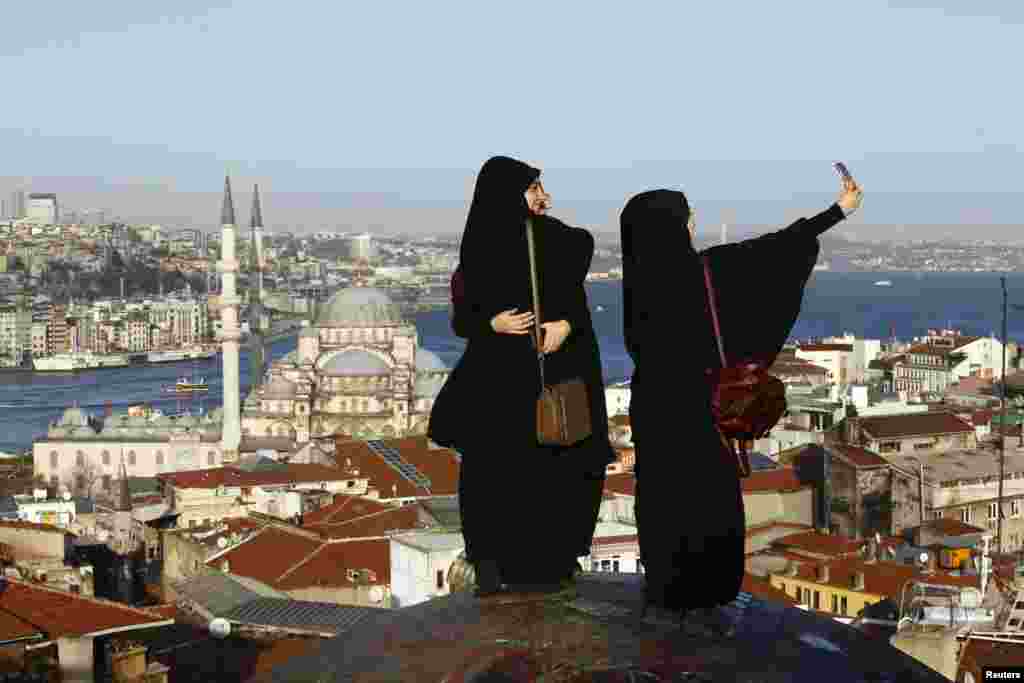 Young women take selfie photographs in front of the New Mosque by the Bosphorus strait in Istanbul, Turkey. A Syrian suicide bomber is thought to be responsible for an attack which killed at least ten people including foreigners in the heart of Istanbul&#39;s historic Sultanahmet tourist district on Tuesday.