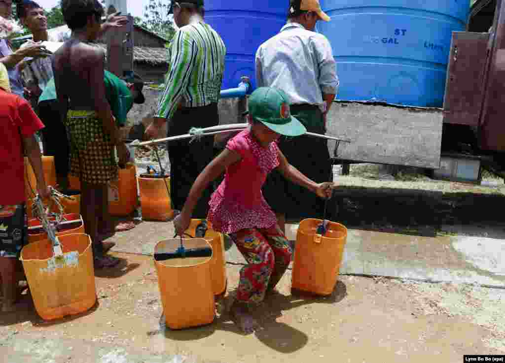 A child carries buckets of water as people wait to get drinking water from a donor&#39;s truck at a village of Dala township at outskirts of Yangon, Myanmar. Myanmar suffers from drought and drinking water shortages in at least 10 regions due to the El Nino weather phenomenon.
