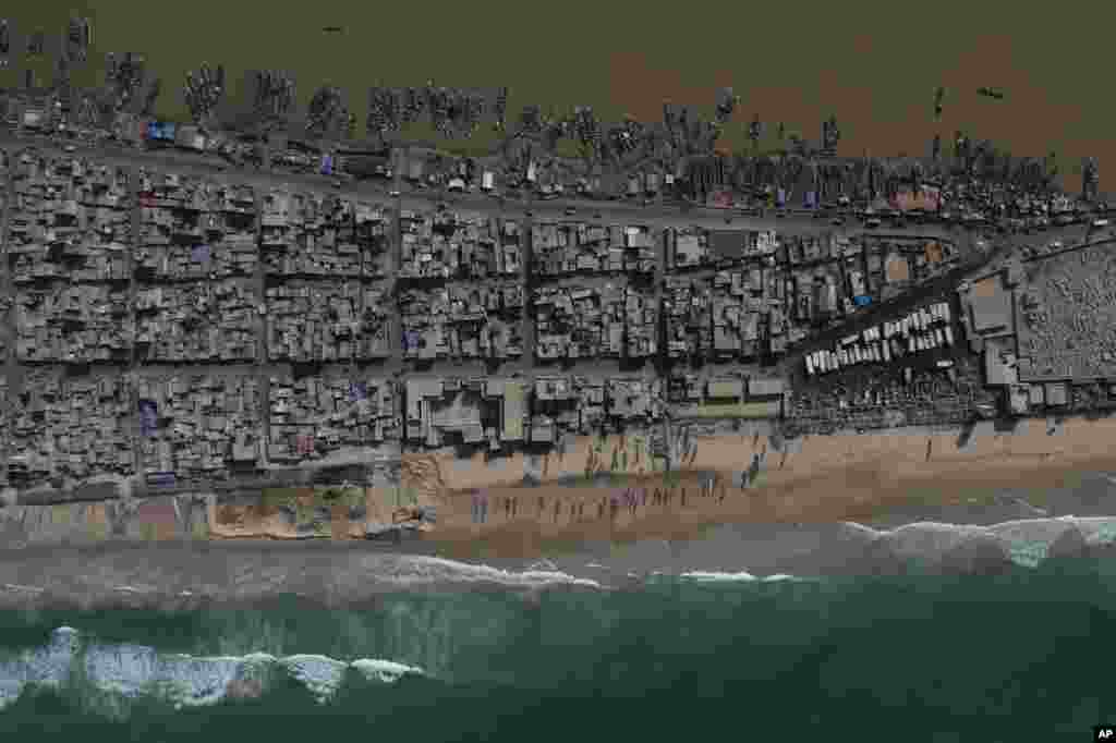 In this image taken by drone, houses sit between the Senegal River, top, and the Atlantic Ocean beach that has been affected by erosion in Saint Louis, Senegal.
