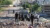 People gather amidst the rubble and damaged vehicles following reported air strikes by the Syrian regime ally Russia, in the town of Kafranbel in the rebel-held part of the Syrian Idlib province on May 20, 2019. 