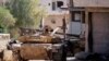FILE - A Syrian army soldier holds a Syrian flag as he stands on a military vehicle in Khan Sheikhoun, Idlib, Syria, Aug. 24, 2019.