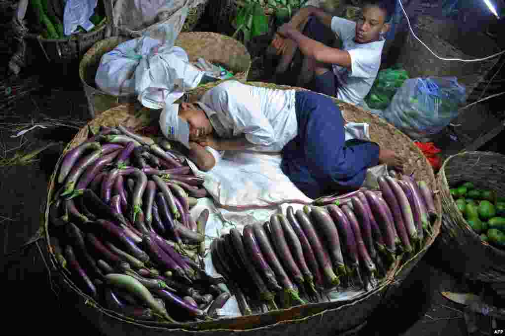 Seorang pria tertidur di keranjang sayuran di sebuah pasar di Rangoon, Burma.