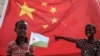FILE - A boy holds the Djiboutian national flag in front of the Chinese national flag as he waits for Djibouti’s president, Ismaïl Omar Guelleh, before the launching ceremony of a China-financed 1,000-unit housing construction project in Djibouti, July 4, 2018.