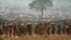 FILE - Refugees who fled the genocide in Rwanda carry water containers back to their huts at a refugee camp in Tanzania on May 17, 1994. French President Emmanuel Macron reportedly will say on April 7, 2024, that the genocide could have been stopped by France and its allies.