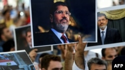 People hold pictures of the late former Egyptian President Mohamed Morsi during a symbolic funeral ceremony, June 18, 2019 at Fatih mosque in Istanbul, Turkey.