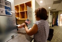 FILE - Isabel Ruiz, right, receives a U.S. flag from Supervisory Immigration Services Officer James Fobert after she passed her citizenship interview in Newark, N.J.