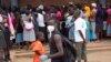 A man wearing a mask is seen near a food queue in Harare, Zimbabwe, March 25, 2020. 