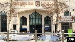 Quelques personnes passent devant une succursale de la Banque Melli à Téhéran le 23 janvier 2012.