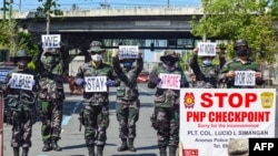 Police hold up placards reminding people to stay at home amid concerns of the spread of COVID-19 in Manila on March 31, 2020.
