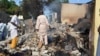 Residents watch as two men walk amidst rubble after Boko Haram militants raided the town of Benisheik, west of Borno State capital Maiduguri September 19, 2013.