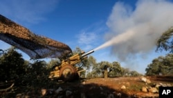Turkish-backed rebel fighters fire a howitzer toward Syrian government forces' positions near the village of Neirab in Idlib province, Syria, Feb. 20, 2020. 