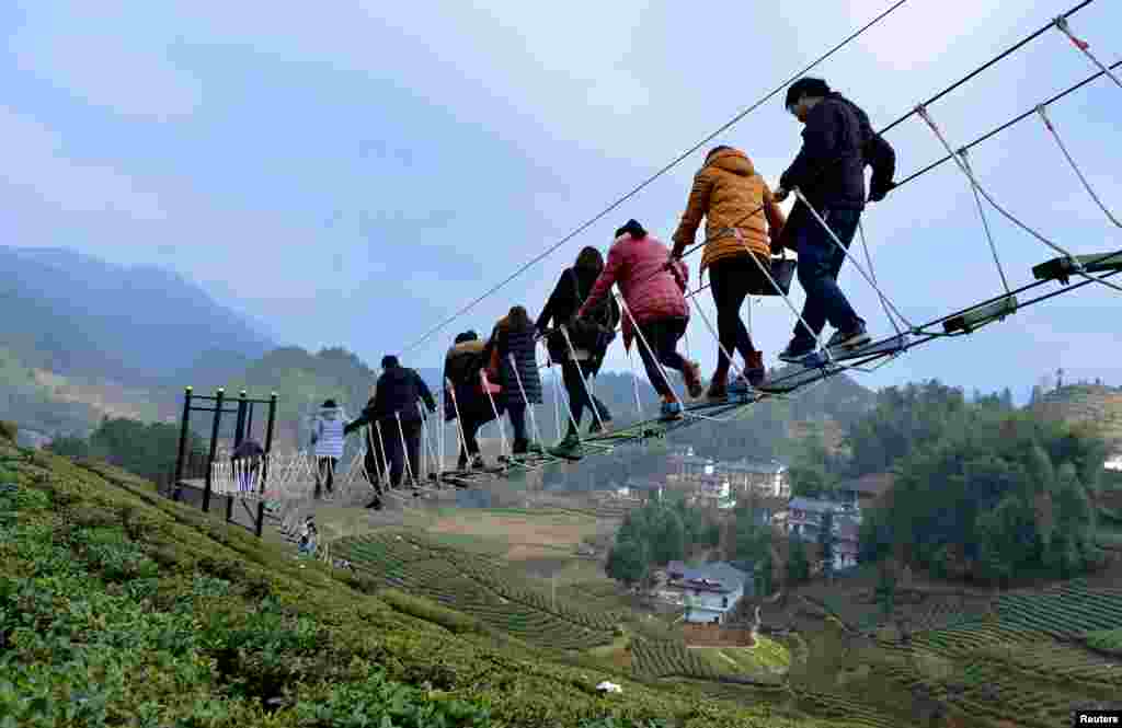Tourists walk above a tea plantation in Enshi, Hubei province, China, Dec. 27, 2015.