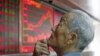 File - An investor watches an electronic board showing stock information at a brokerage office in Beijing, China, July 2015.