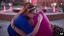 Christina Walls, left, and Diana Lennon embrace during a candlelight vigil July 24, 2015, to honor victims killed a day earlier in a movie theater in Lafayette, Louisiana. 