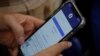 Seorang pengguna Facebook login di ponselnya di sebuah kafe,19 November 2020. Pegawai Komisi Penyiaran Indonesia (KPI) berinisial MS yang menjadi korban pelecehan seksual meminta warganet untuk tidak berkomentar negatif terhadap keluarga pelaku. (Foto: REUTERS/Kham)