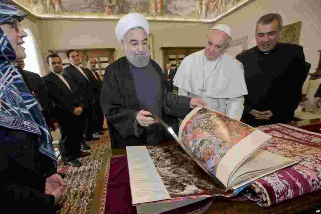 Iranian President Hassan Rouhani, left, leafs through a book he gave to Pope Francis as a gift, during their private audience at the Vatican.