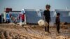 Syrian children carry jugs to fill with water in Washukanni camp, on Dec. 16, 2019, which was recently established on the outskirts of Hasakeh city for people displaced from the northeastern Syrian town of Ras Al Ain.